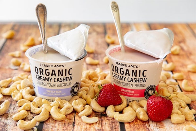 New at Trader Joe's; two tubs of yogurt stand surrounded by cashew nuts and two strawberries