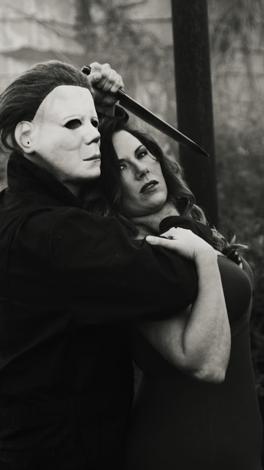 Husband Evan in costume as Michael Myers holding a knife over wife Sabrina as a prank