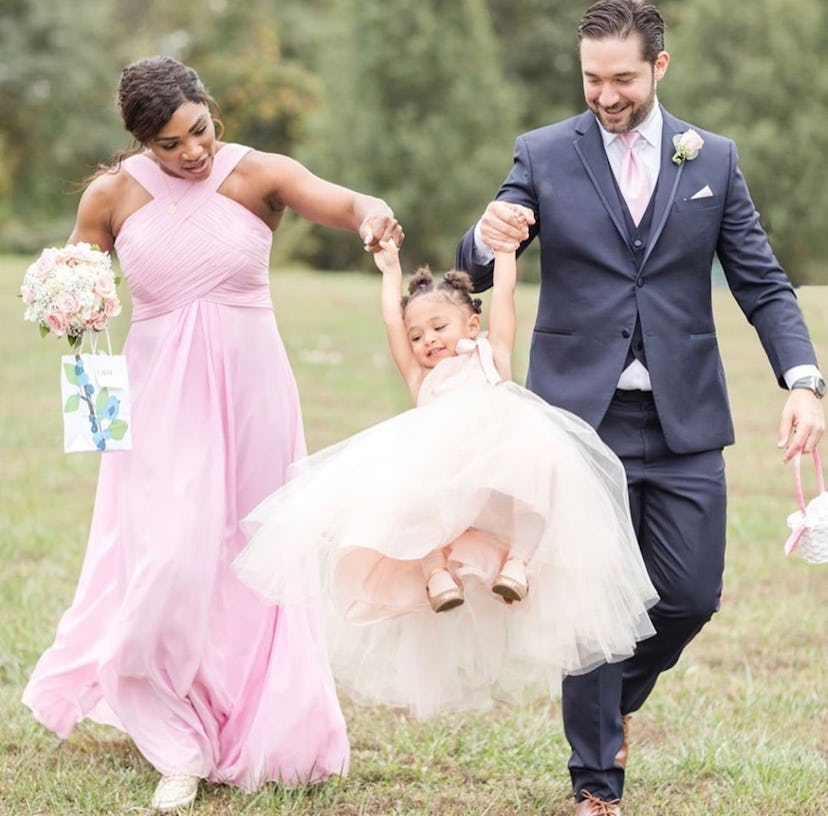 Serena Williams in a pink dress and Alexis Ohanian in a navy suit with their flower girl daughter