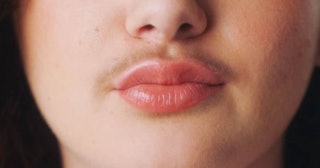 A close-up of a woman's lower face section with a moustache