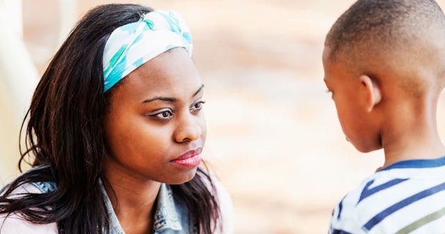 A mother wearing a blue hair piece, looking at her son, unable to answer his questions about God.