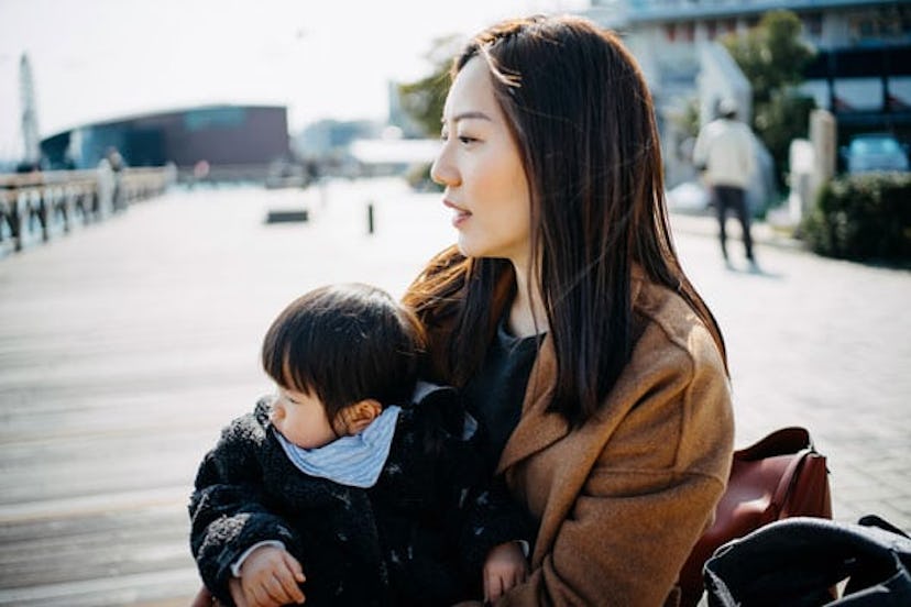 A woman sitting on a bench, holding her child in her lap.