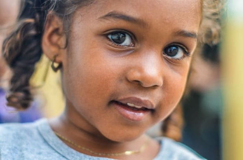 Little girl with a curly hair and a golden necklace 