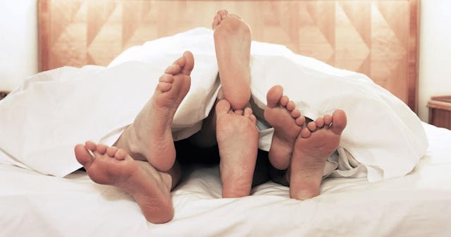 Three pairs of legs under the sheets