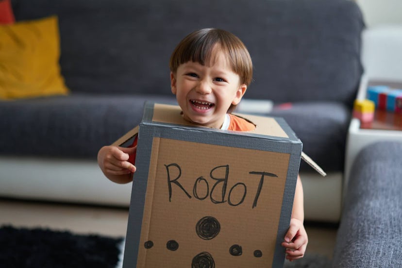 2-3 years cute child is wearing cardboard robot costume at home