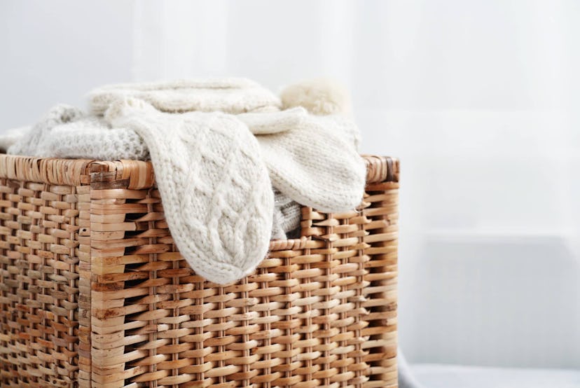Rattan baskets with winter clothes and white mittens closeup