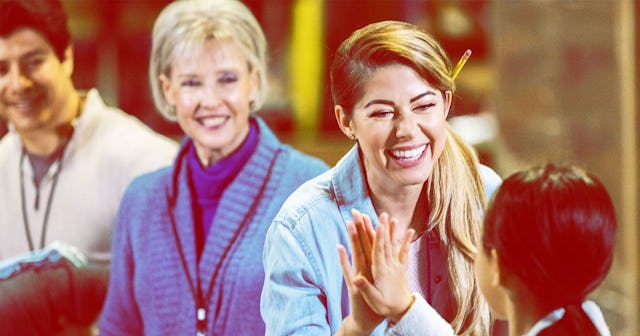 A woman giving a high-five to the girl and smiling at a PTO fundraiser
