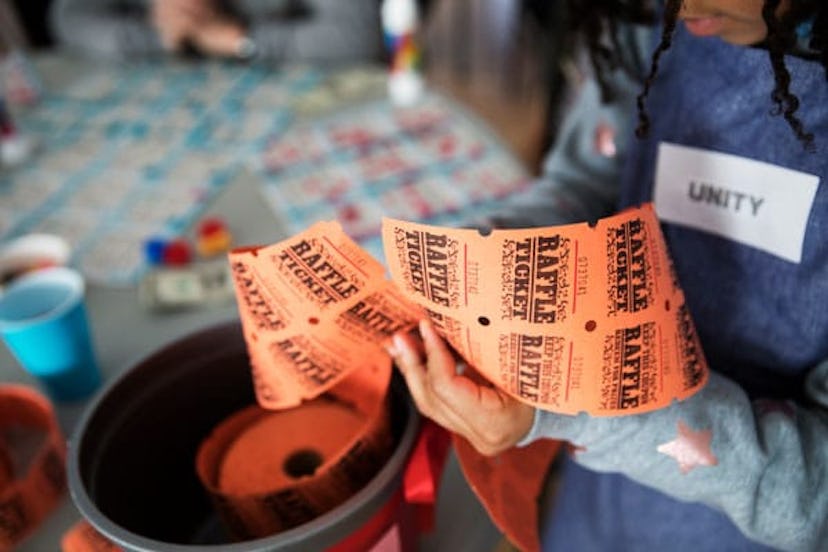 A woman cutting orange tickets from a big container for a PTO fundraiser