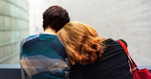 Two people resting on each other's shoulders while they are sitting on the bench