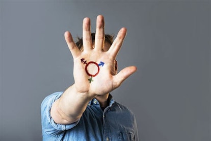 An individual wearing a blue shirt is showing a transgender sign that is painted on their palm
