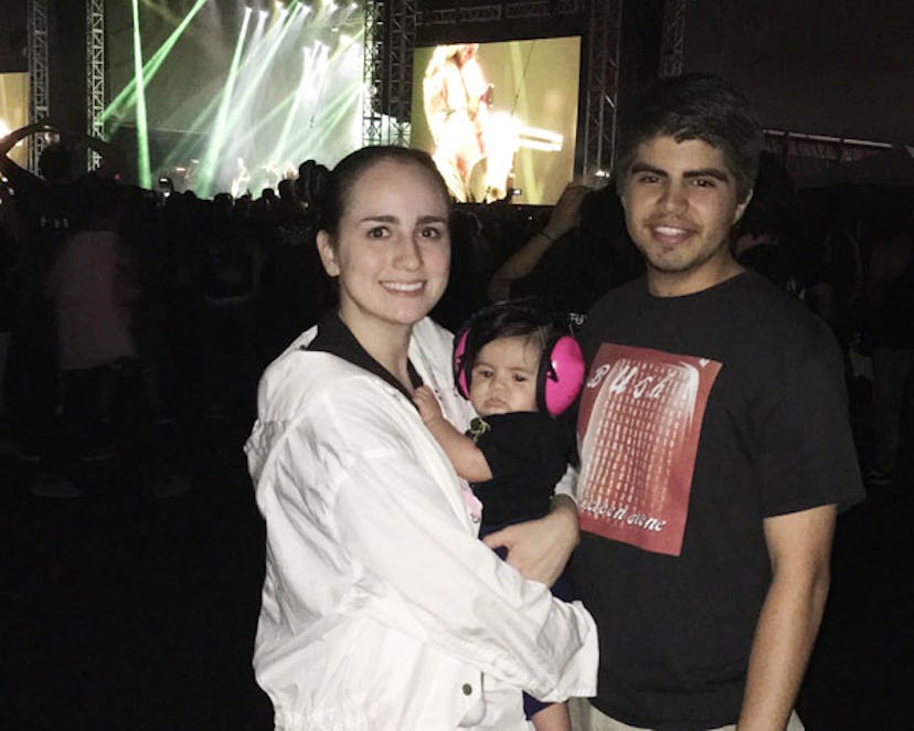 Parents and Maxwell at a rock concert at night, with the stage in the background. The mom is holding...