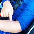 Small boy sitting in a car with a plaster on his left hand because of a bite mark