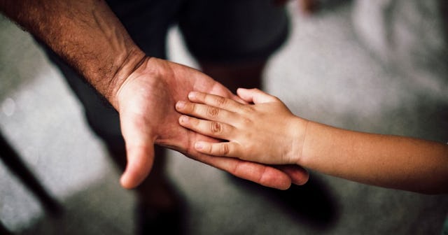 A child's hand on his parent's palm