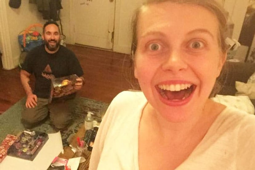 A selfie of a woman and man, smiling, while he is opening Christmas presents.