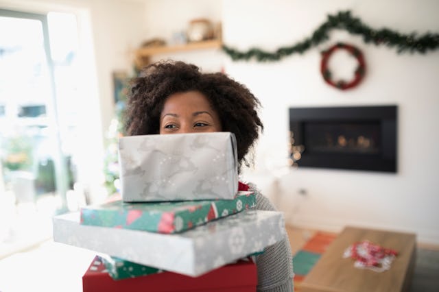 Portrait woman carrying stack of Christmas gifts
