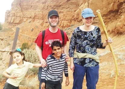 A mother and a father, with their daughter and blind son, on a hike in a canyon.