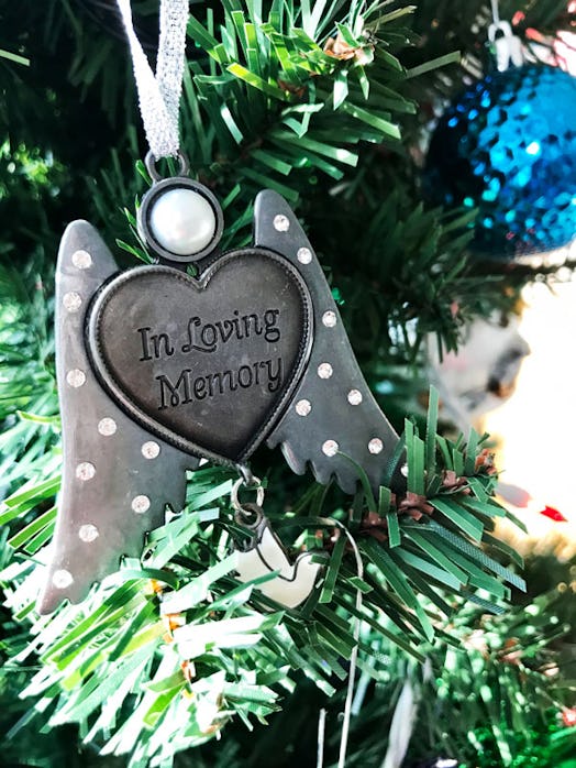 A heart-shaped Christmas ornament with wings that has "in loving memory" engraved on it 