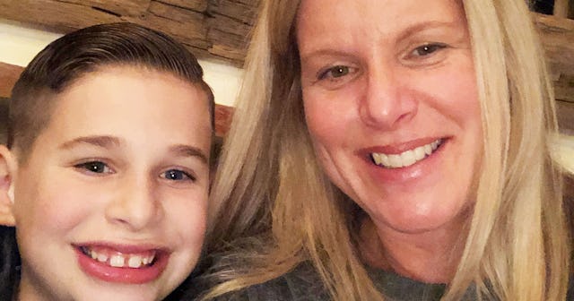 A kid smiling while posing for a selfie with his mother