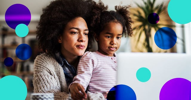 A curly black-haired woman in a beige sweater and her daughter sitting in her lap, both looking into...