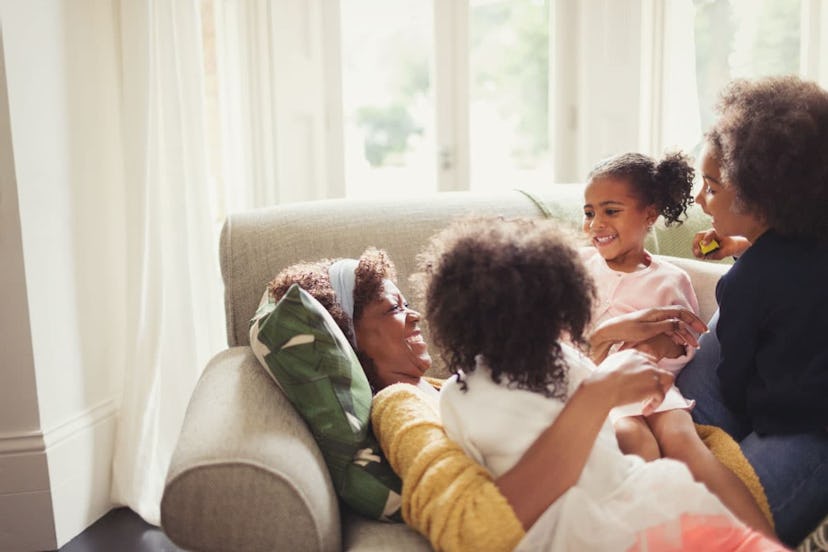 Mom lying on a couch and laughing with her three daughters