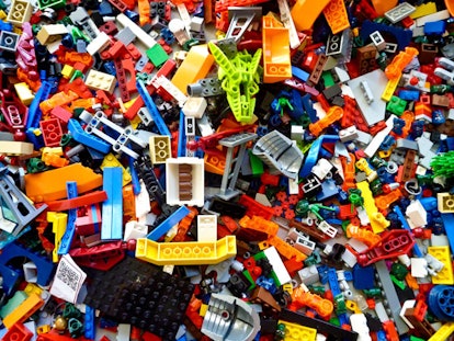 A large pile of Lego toy pieces stacked on each other in various shapes, sizes and colors