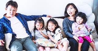 Parents with their three kids sitting on a couch 