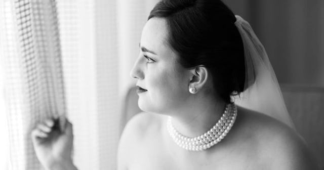 Woman in a wedding dress looking out the window