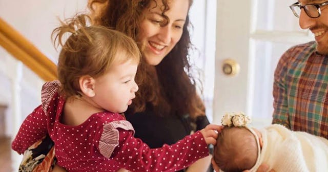 Parents bringing a newborn baby home from the hospital and introducing her to an older sister