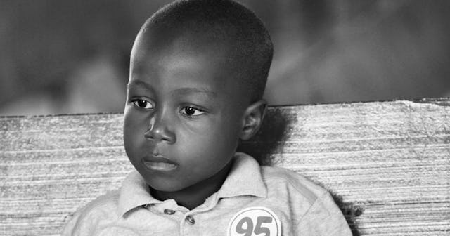 A toddler boy in a polo shirt with a neutral facial expression in black and white