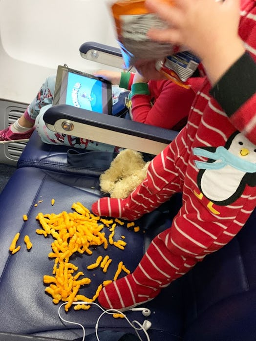 A toddler spilling chips all over his seat on the airplane