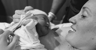 Dani Sherman-Lazar laying and holding her newborn baby in a hospital bed in black and white