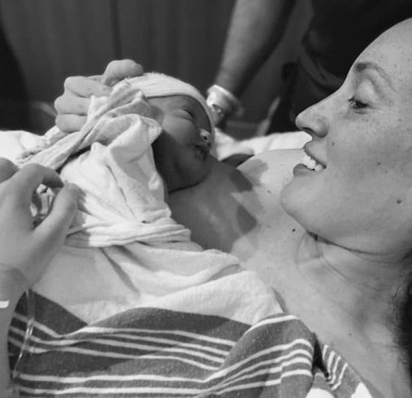 Dani Sherman-Lazar laying and holding her newborn baby in a hospital bed in black and white