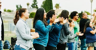 People standing and applauding on a street