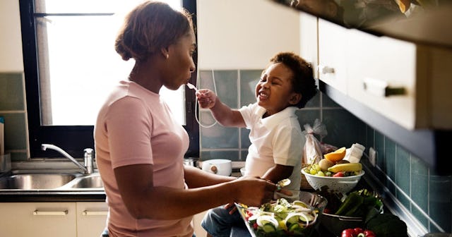 kid feeding mother with cooking food in the kitchen