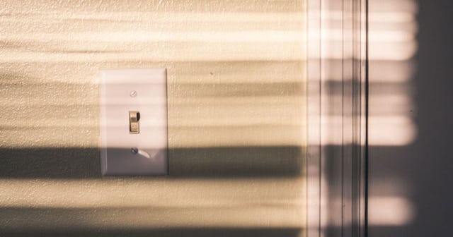 A light switch in a curtain shadow