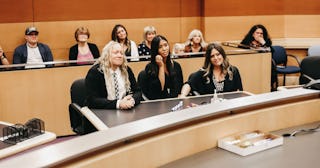 Multiple people sitting in a courtroom during the adoption of an adult after aging out of the foster...