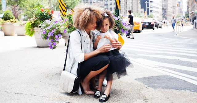A single mother holding her daughter on the street during a sunny day