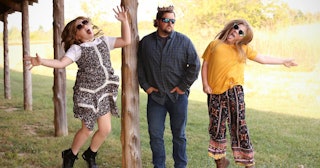 A father with two daughters that are jumping and dancing