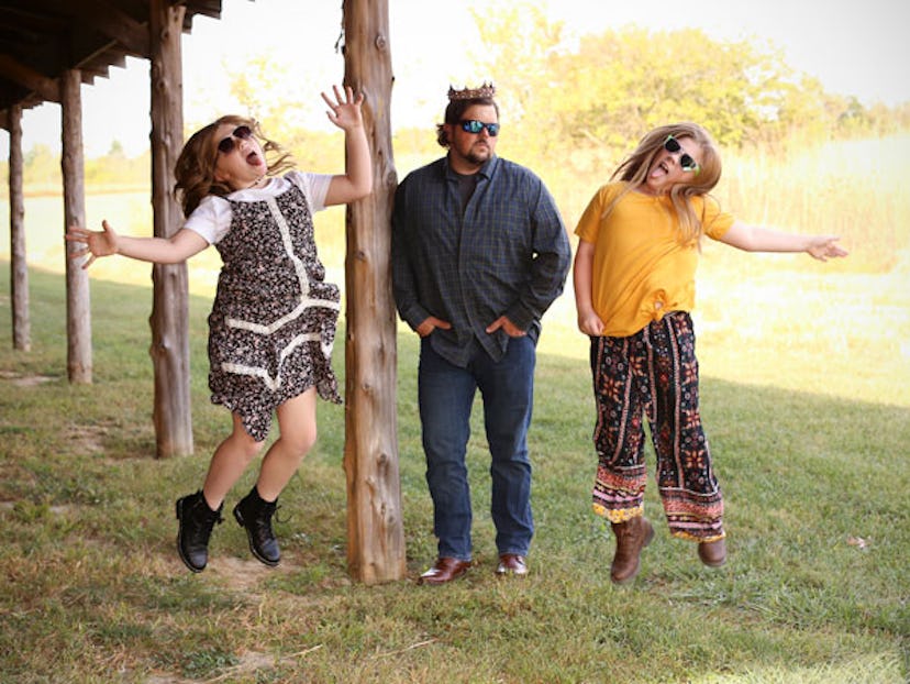 A father with two daughters that are jumping and dancing