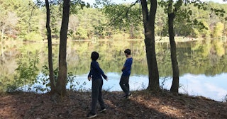 two kids by water in the woods