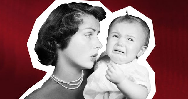 Woman wearing green dress and pearls holding a crying baby in a pink dress