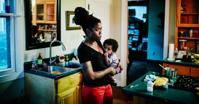 I am Unapologetically One and Done: Mother holding infant in kitchen of home after dinner with famil...