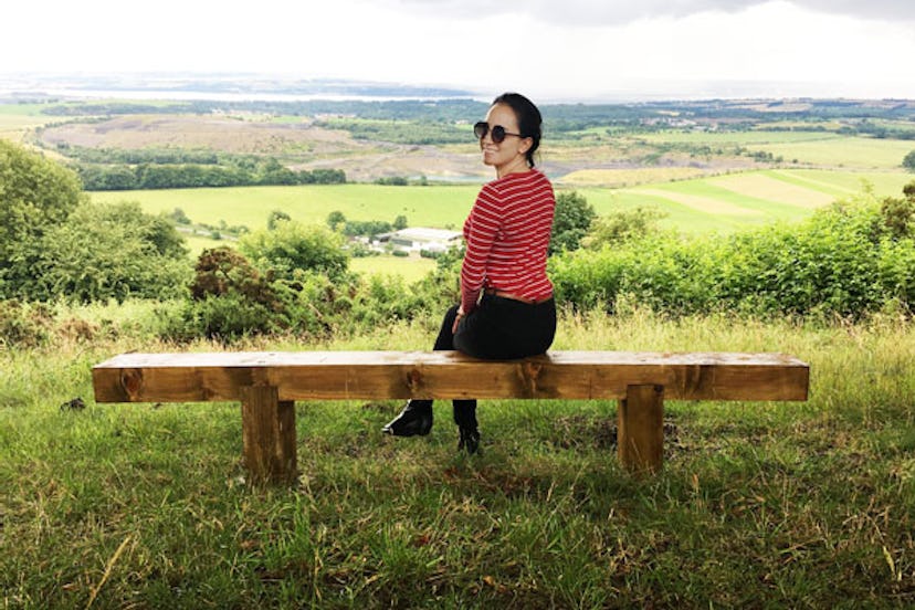 Katarina Garcia sitting on a bench in nature dressed in a striped T-Shirt 
