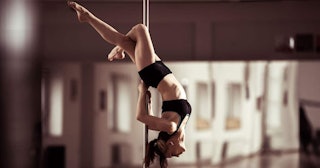 Pole Dancing Is Now Officially Recognized As An International Sport: Female dancer holding herself u...