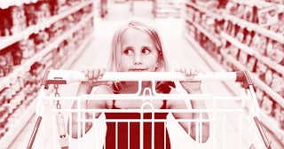Young girl pushing shopping cart in supermarket aisle