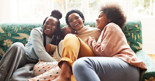 ortrait of happy young woman embracing girls while sitting on sofa at home