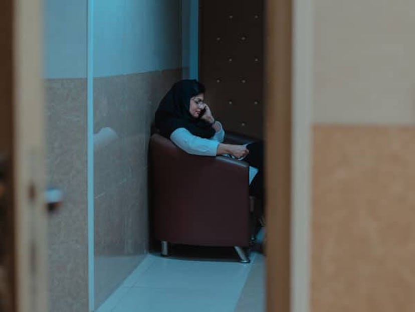 A woman sitting and speaking on her phone in a doctor's office hallway