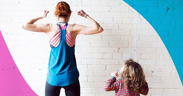 A mother flexes her arm muscles in front of her son.