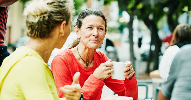 Smiling mature female friends enjoying breakfast at outdoor cafe