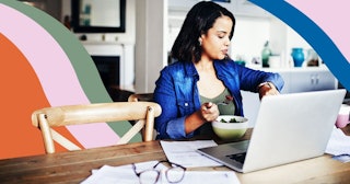 young woman checking her watch and having a salad while working from home